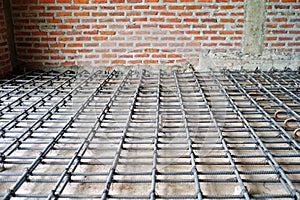 Steelwork for reinforcement of concrete floor with brickwork background