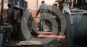 Steelworker in a Foundry Pouring Molten Metal into Sand Molds on a Conveyor Belt photo