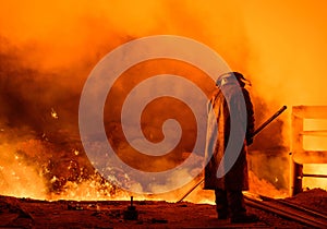 Steelworker near a blast furnace with sparks. Foundry. Heavy industry