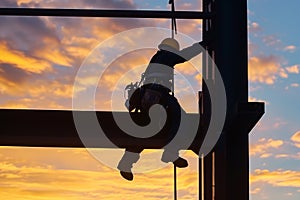 steelworker perched high with sunset skies behind