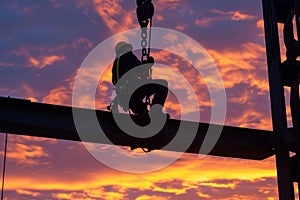 steelworker perched high with sunset skies behind photo