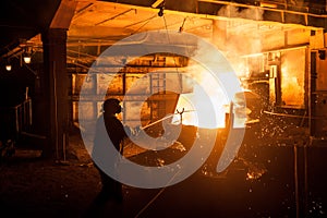 Steelworker when pouring liquid titanium from arc furnace photo