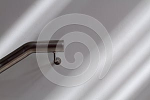 Steely handrail and light and shadows on white wall