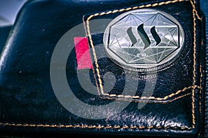 Steem cryptocurrency coin on leather wallet.