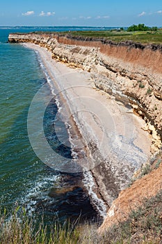 Steep clayey and shell rock shore overgrown with wild steppe vegetation on the island of Berezan, Ukraine