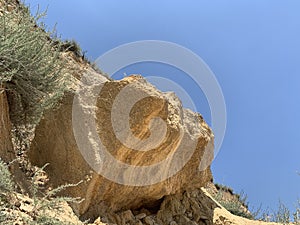 Steep cliff of the mountain by the sea. Sandy mountain by the ocean. A hill near the coast