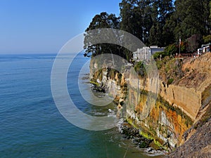 Steep cliff at  the Pacific Ocean with house perilously close to the abyss