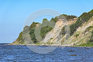 Steep coast with shrub vegetation and erosion of clay and boulders in a bay on the Baltic Sea near the tourist resort Boltenhagen