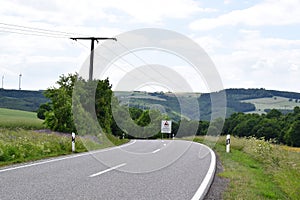 steep curvy road into Elztal with a warning sign in three languages: slow down