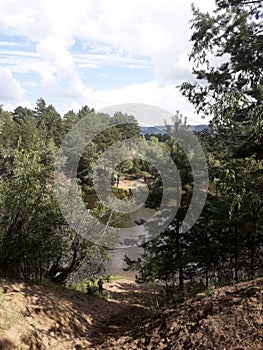 Steep descent to the forest lake. Firs and willows grow on the left and right.