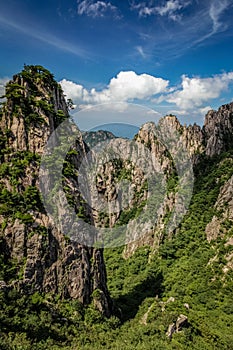 Steep mountain pinnacle on the left casting a short shadow on the green valley in Huang Shan China