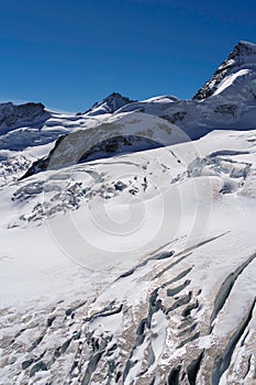 Steep mountain slope with cracks and crevasses in the glacial ice at Jungfraujoch - vertical