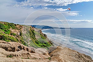 Steep rocky mountain overlooking parachuters and ocean in San Diego California