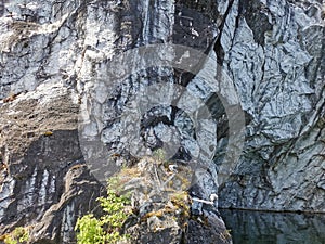 A steep slope of a flooded Marble Canyon with a gull`s nest in the Ruskeala Mountain Park on a sunny summer day