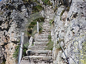 Steep stairway carved out of stone on a mountain path. Steel cables on its sides. Orobie. Italian Alps