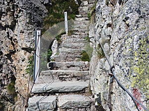 Steep stairway carved out of stone on a mountain path. Steel cables on its sides. Orobie. Italian Alps