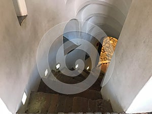 Steep stone spiral stairs going down from the steps