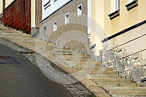 A steep street with staircase on sidewalk