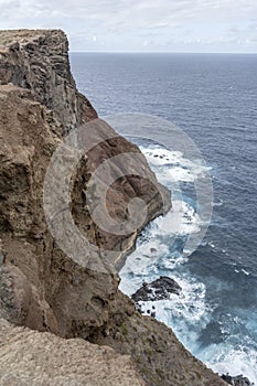Steep volcanic cliffs on ocean waves dashing  at Ponta do Rosto, Madeira photo
