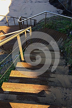 Steep wooden staircase leading down, sand scattered on the steps