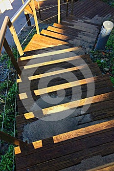 Steep wooden staircase leading down, sand scattered on the steps