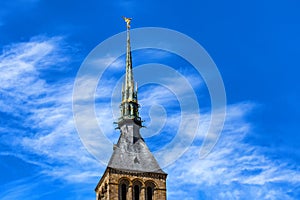 Steeple of Mont Saint-Michel abbey in France against blue sky