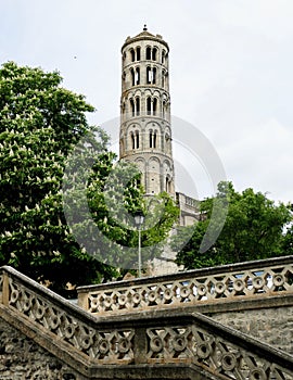 Steeple of the old bishopric of UzÃ¨s between two trees in the forground