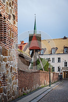 Steeple and old stone buildings along a cobblestoned street in the city center of Lund Sweden