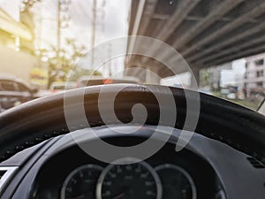 Steering Wheel Against Blurred Speedometer and Traffic Background