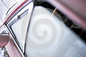 The steering wheel of a cintage car peeking through the window