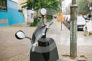 The steering wheel of an electric scooter is in the foreground, in the background is an urban view of Berlin street.