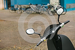 The steering wheel of an electric scooter is in the foreground, in the background is an urban view of Berlin street.