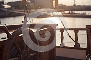 Steering wheel of an old wooden sailing ship in sunset