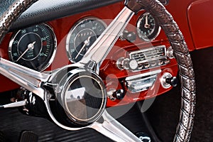 Steering wheel, speedometer, revs, clock dials, radio scale, buttons and knobs on front panel red coupe old timer sports car