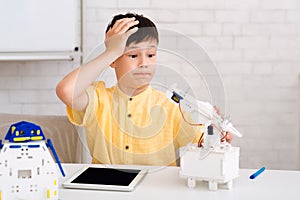 Stem education. Dismayed boy creating robot and made mistake photo
