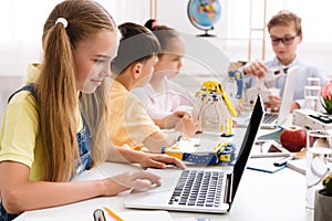 Stem education. Girl programming diy robot with laptop