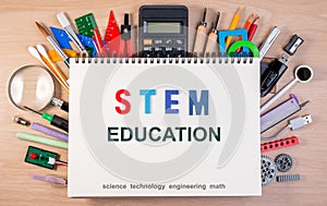 STEM education text on notebook over school supplies or office s