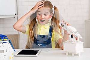 Stem lesson. Surprised girl constructing diy robot at class