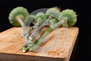 Stem of poppy on a kitchen board. White liquid flowing out of the poppy plant