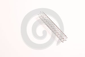 A stent used in angioplasty procedure placed on a white surface.