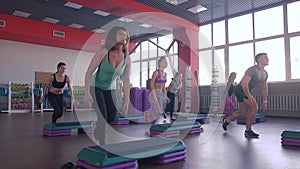 Step aerobics exercise class - group of people exercising on steppers with the trainer.
