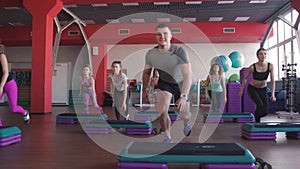 Step aerobics exercise class - group of people exercising on steppers with the trainer.