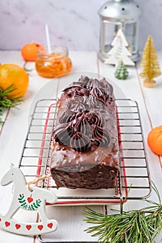 Step-by-step decoration of a carrot cake with chocolate glaze, ganache and candied fruits in a Christmas style on a light wooden