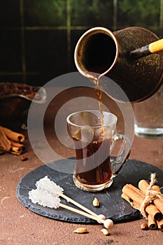 Step by step preparation of Turkish coffee on the sand. Step five, pouring the finished coffee from the cezve into a glass cup