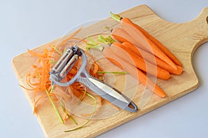 Step by step cooking. Pealed carrots on a wooden cutting board on a grey background.