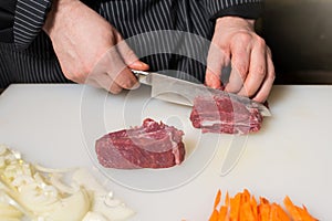 Step-by-step process and stages of cooking oriental cuisine - pilaf. The cook cuts a piece of meat for pilaf.