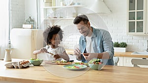 Stepfather teaches african daughter cut diverse vegetables for vegetarian salad