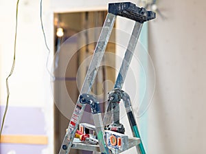 Stepladder with tools in empty room, renovation works