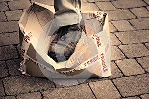 Stepping on a box of fragile items. Conceptual image shot