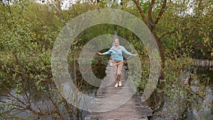 Stepping onto a wobbly suspension bridge over a river, a woman confronts her fear and walks forward.